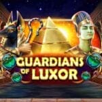 Guardians of Luxor title screen showing an Ancient Egyptian temple with golden statues, piles of coins, and a glowing pyramid in the background. Two large figures, Anubis on the left and an Egyptian pharaoh on the right, frame the golden game title text at the center, decorated with green scarab beetles.